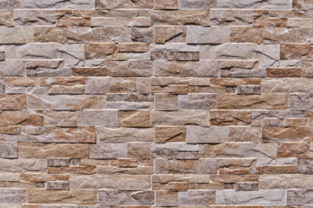istock Patterned wall tiles as split natural stone background. Simulated brown natural stone facade, wall tiles texture. 1359688012