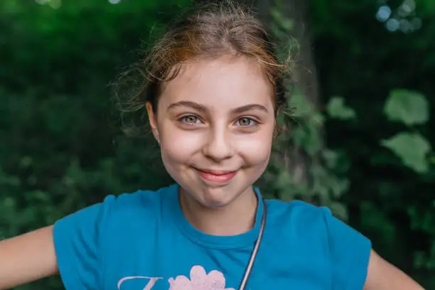 Close up portrait of a ten-year-old russian girl smiling to the camera in an urban park