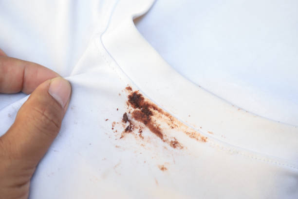 hand zeigt schmutzigen choclate-fleck auf kinderhemd vom essen für reinigungskonzept in der hausarbeit klar - chocolate sauce stock-fotos und bilder