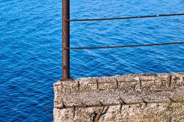 an old concrete and metal structure or fence against a background of blue water