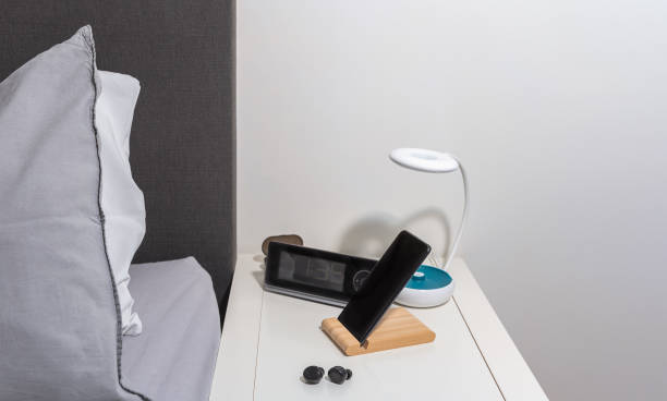 istock smartphone on the bedside table with lamp, headset, clock and bed as background 1359693147