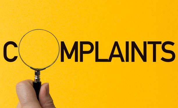 Complaints Hand holding magnifying glass on yellow background. O letter replacement with magnifying glass. complaining stock pictures, royalty-free photos & images