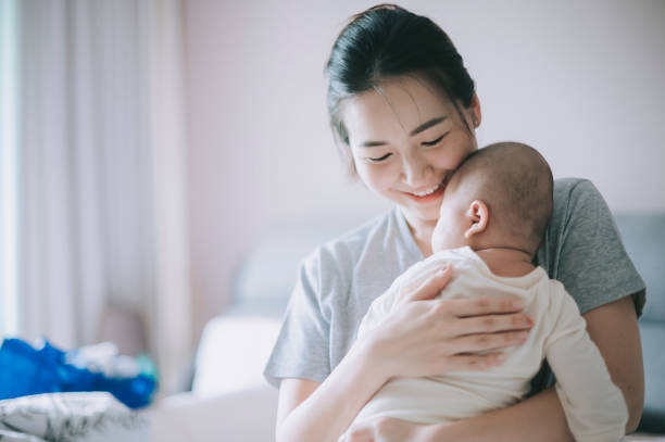 asiatisch-chinesische mutter, die sich mit ihrem kleinen jungen zu hause verbindet - baby newborn chinese ethnicity asian ethnicity stock-fotos und bilder
