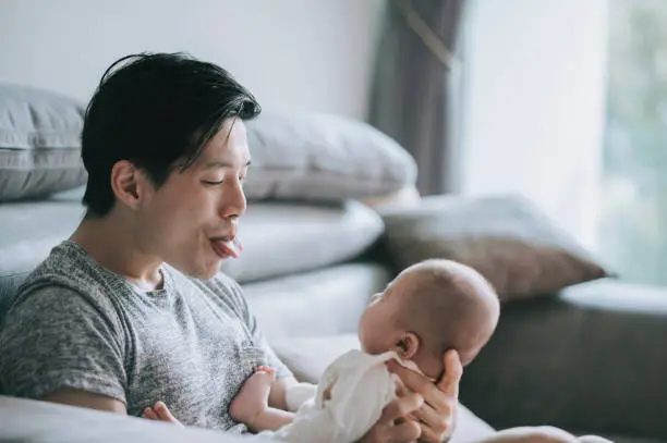Photo of Asian Chinese young father bonding time playing with his baby boy son at living room during weekend