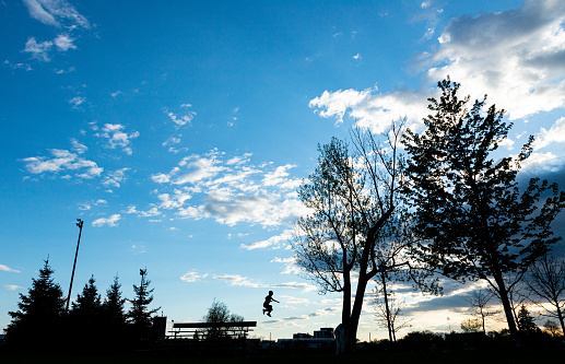 Silhouette of child jumping in the park during sundown