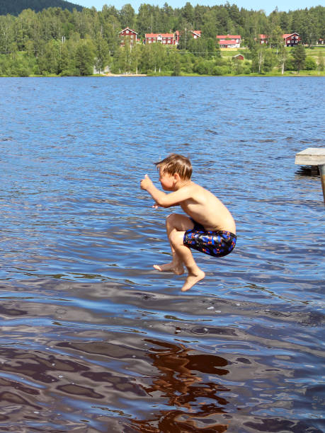 istock Young boy jumping into the water from jetty 1359702213