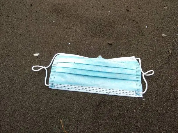 Photo of Face mask on the floor on a black beach background