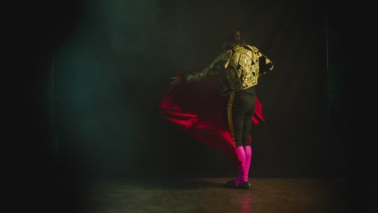 Male dancer or toreador imitating moves of matador bullfighter on black smoky background .  Man bullfighter dressed in bullfighting costume . Shot on ARRI Alexa cinema camera in Slow Motion