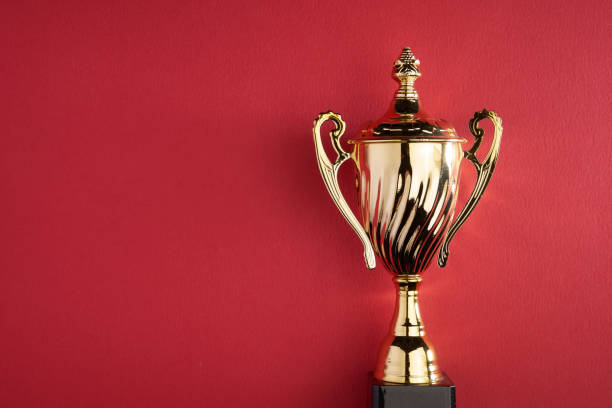 istock gold colored trophy against red background 1359707498