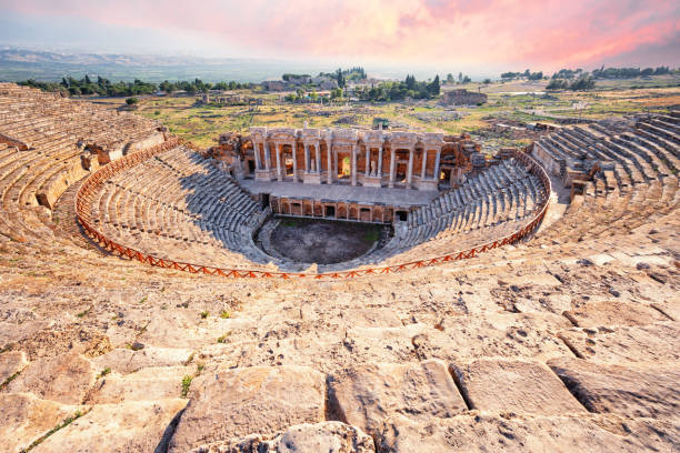 劇的なピンクの空の下でヒエラポリスの古代都市の円形劇場 - hierapolis ストックフォトと画像