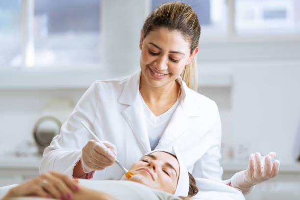 Female dermatologist performing a procedure on a client stock photo