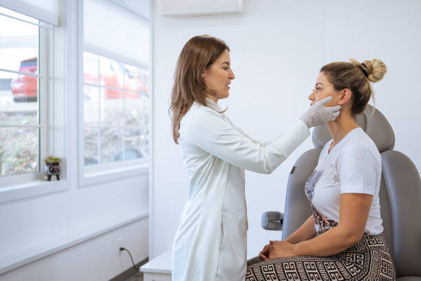 Female dermatologist performing a procedure on a client stock photo