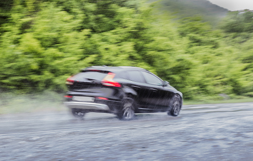 car moves under a downpour on a country road along the forest. Blurry motion
