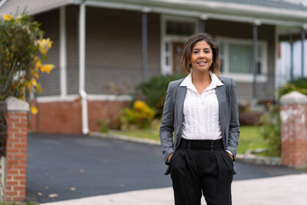 Real female real estate agent in front of a house stock photo