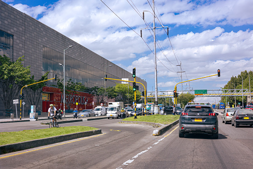 Bogota, Colombia - September 18, 2021: Driver's point of view, driving on the Southbound carriageway of the usually busy Avenida Calle 68, in the Colombian Capital city of Bogota, in South America. It normally has heavy vehicular traffic in the area, at this time of the day. Today, it is fairly free of traffic. In front is a pedestrian footbridge right across the road. To the left of image is the Centro Commercial Metropolis, a popular shopping centre. Horizontal Format.