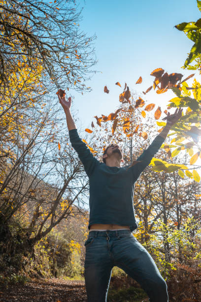 istock close up. young man plays with yellow leaves falling down. vertical composition 1359732826