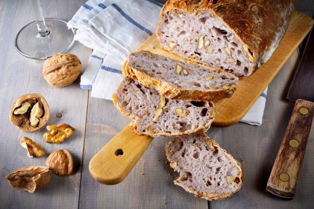 istock Walnut bread cut into slices on wooden table with cutting board and knife. 1359735241