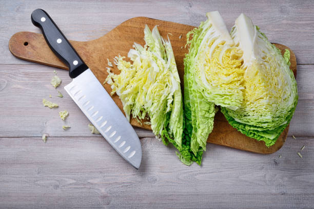 istock Savoy cabbage, cutting board and knife on wooden background. Top view, space for text. 1359735283