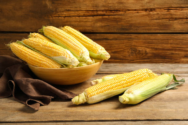 istock Tasty sweet corn cobs on wooden table 1359738435