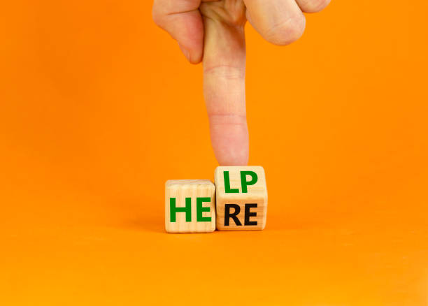 istock Help is here and support symbol. Businessman turns a cube and changes the word help to here. Beautiful orange background, copy space. Business, motivational, support and help is here concept. 1359740829