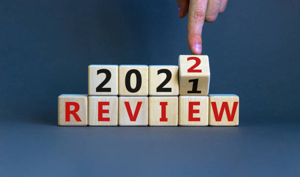 2022 review new year symbol. Businessman turns a wooden cube and changes words 'Review 2021' to 'Review 2022'. Beautiful grey background, copy space. Business, 2022 review new year concept. stock photo