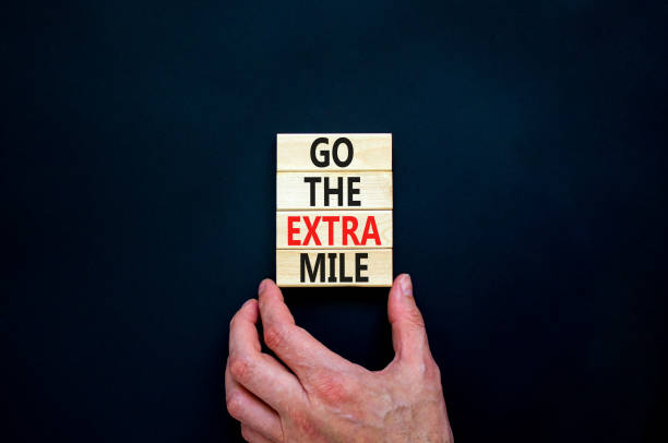 Go the extra mile symbol. Concept words Go the extra mile on wooden blocks. Businessman hand. Beautiful black table, black background, copy space. Business and go the extra mile concept. stock photo