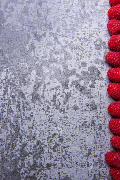 Cracked stone, concrete texture backround, copyspace and right side frame created from fresh raspberries
