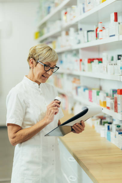 istock Beautiful senior female pharmacist checking medications on a shelf 1359748779
