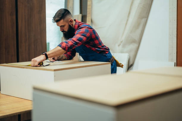 istock Young male carpenter working in workshop and measuring with meter 1359748793