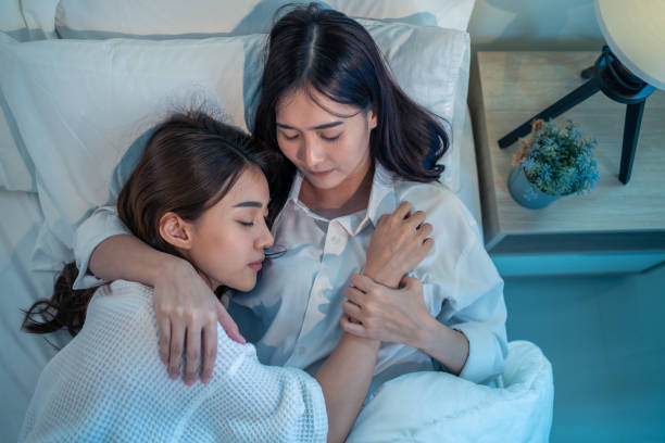 istock Asian beautiful lesbian couple lying down on bed and hugging each other. Attractive romantic girl friend in pajamas spending night leisure time together in bedroom in house. 1359757948