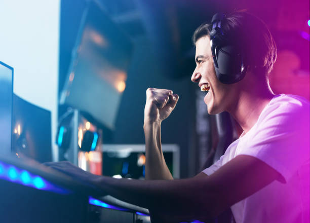 scatto di un giovane che applaude mentre gioca ai giochi per computer - amusement arcade arcade video game sport foto e immagini stock