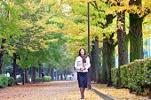 日本女性は、歯木の秋の葉の色の下を歩く