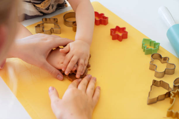 istock Selective focus. Kids making gingerbread cookies with various Christmas cookie cutters. Gingerbread dough. Family Christmas moments 1359777912
