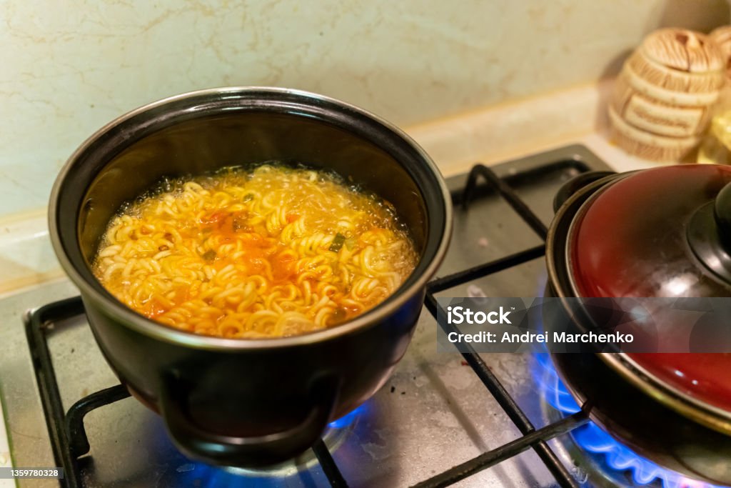 instant noodles in a saucepan are cooked on a gas stove close-up Broth Stock Photo