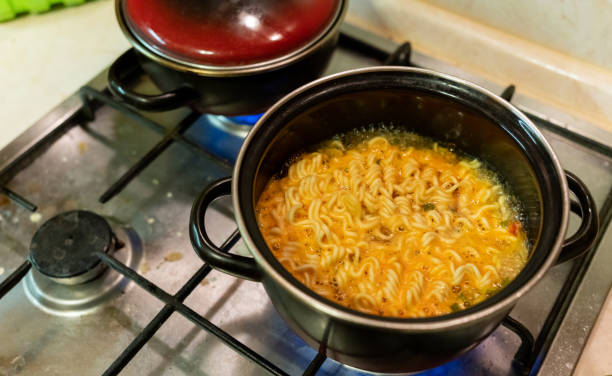 instant noodles in a saucepan are cooked on a gas stove close-up stock photo