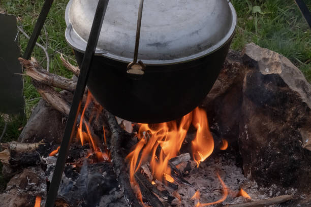 istock Aluminium pot hanging on tripod above campfire. 1359782320