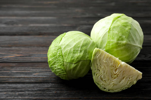 istock Ripe white cabbage with water drops on black wooden table 1359786809
