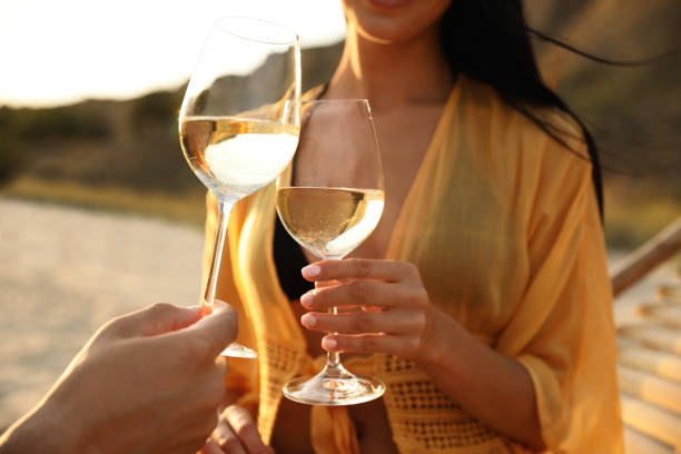 istock Romantic couple drinking wine together on beach, closeup 1359787499