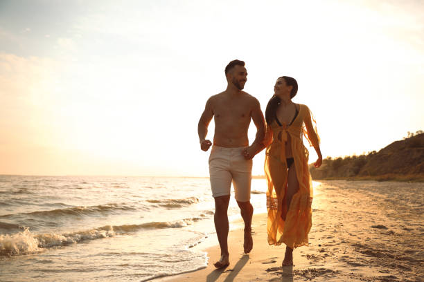 istock Happy young couple running together on beach at sunset 1359788582