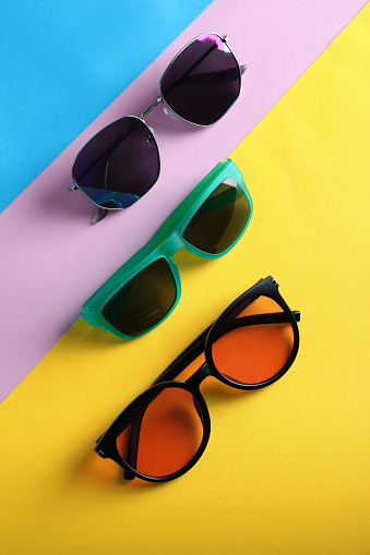 Many stylish sunglasses on color background, flat lay