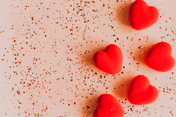 istock Red hearts on pink background with confetti. Valentine's Day template with copy space 1359790080