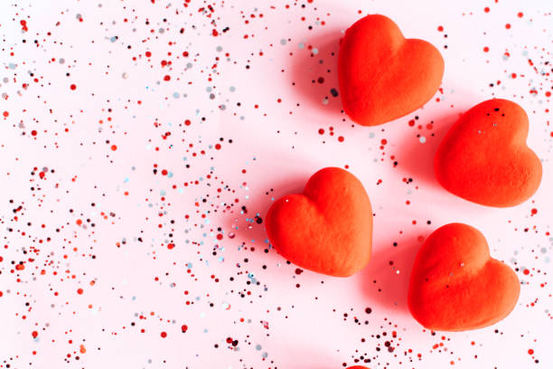 istock Red hearts on pink background with confetti. Valentine's Day template with copy space 1359790084