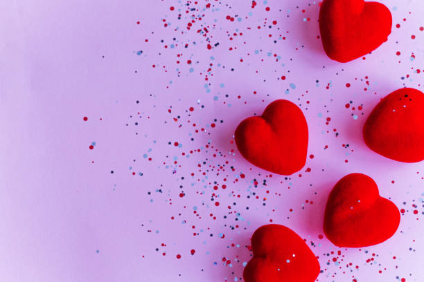 istock Red hearts on pink background with confetti. Valentine's Day template with copy space 1359790308
