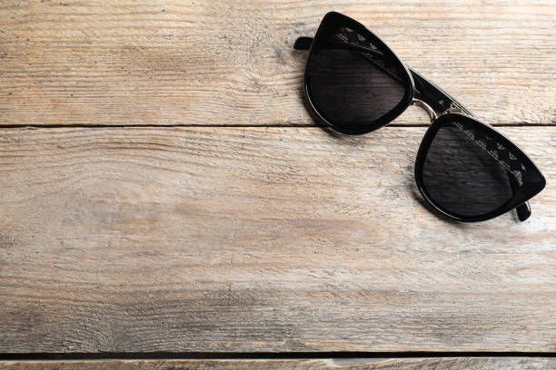 istock Stylish sunglasses on wooden background, top view. Space for text 1359793141
