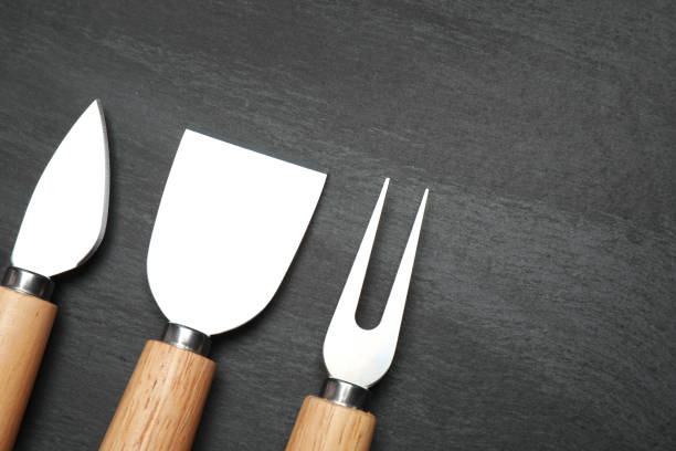 istock Cheese knives and fork on black background, flat lay. Space for text 1359794977