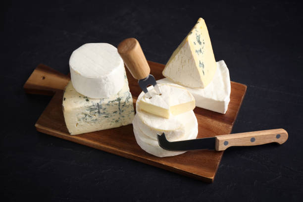 istock Different types of cheese, knife and fork on black table 1359795388