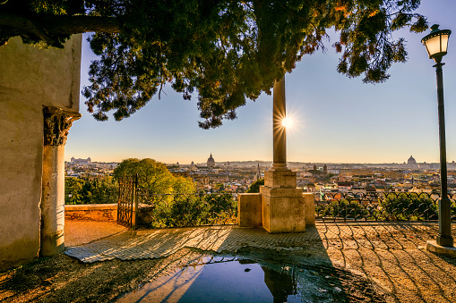 A suggestive sunset over the rooftops of Rome seen from the viewpoint terrace of the Pincio Gardens, in the historic heart of the Eternal City. The terrace of the Pincio Gardens, one of the most visited and loved places in Rome, is the culmination of the west side of Villa Borghese, the largest public park in the heart of the Italian capital. From this belvedere you can enjoy a breathtaking 180 degree view of the historic center of Rome, in the setting of some of the most beautiful gardens in the city. Considered the green lung of Rome, Villa Borghese is the largest public park in the city with almost 80 hectares of extension, where residents and tourists can spend hours of relaxation and silence among tree-lined avenues, ponds and Italian and English-style gardens surrounded by trees and ancient pines. In 1980 the historic center of Rome was declared a World Heritage Site by Unesco. Super wide angle and high definition image.