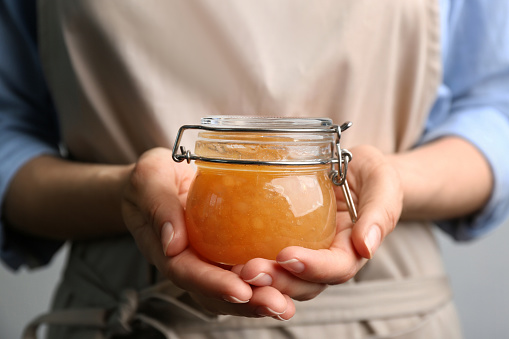 Woman with jar of delicious pear jam, closeup