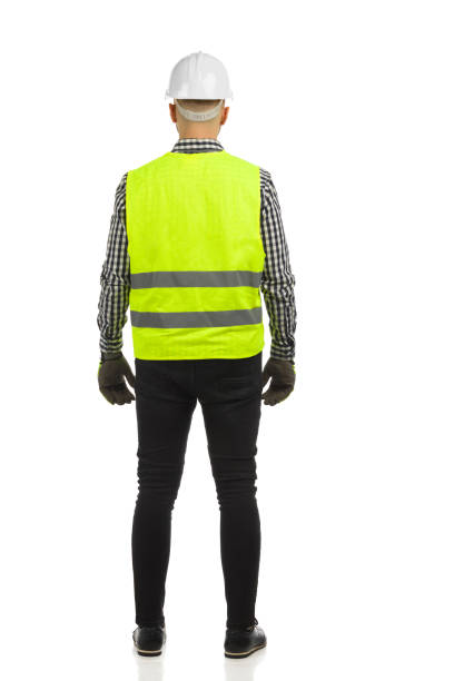 istock Engineer in white hardhat and reflective waistcoat. Rear view. Full length on white background. 1359799582