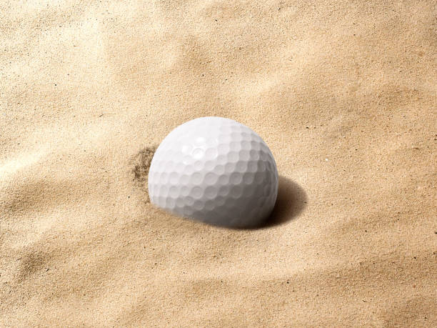 istock Sunlit golf ball with shadow in unraked sand trap. Macro with shallow dof 1359801088